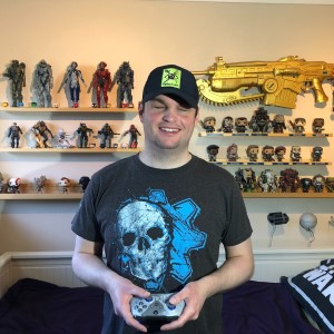SightlessKombat in front of his gaming collection with an Xbox controller