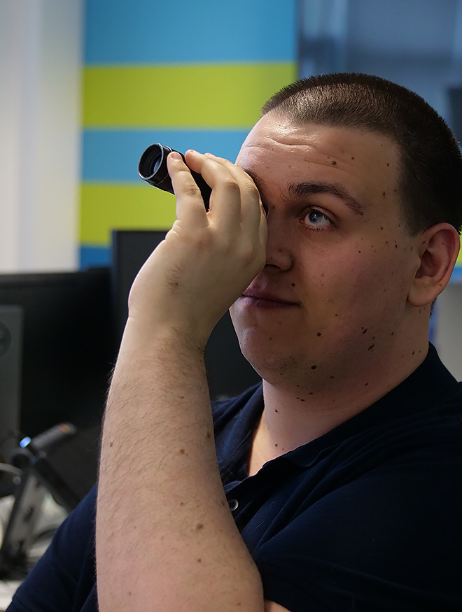 A young man using a monocular viewfinder in an office