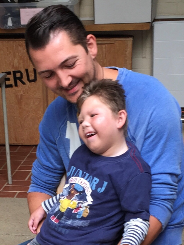 A smiling man holding a happy young boy