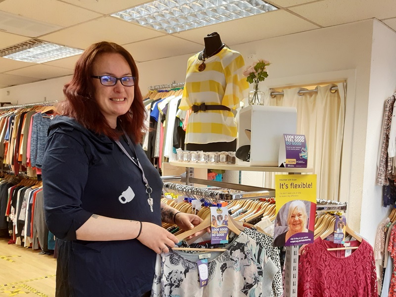 Volunteer Lindsay Sumner sorts through a rail of clothes in a Scope shop