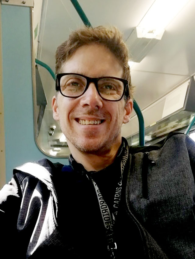 A smiling man sitting on a train