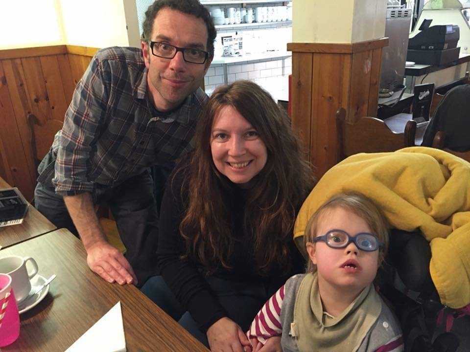 A man, woman and child smile next to a table.