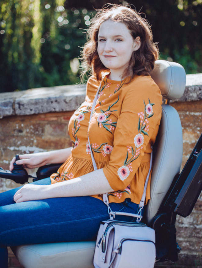 A young smiling woman in a power chair